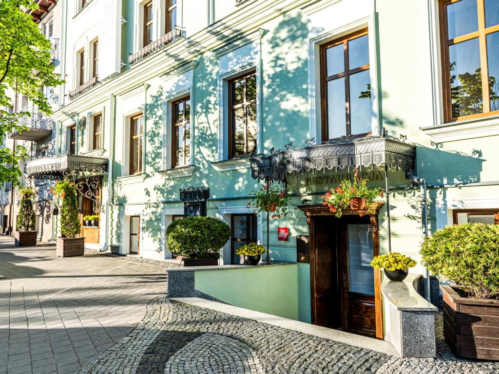 Pastelowy budynek z ozdobnymi daszkami nad wejściem i roślinami