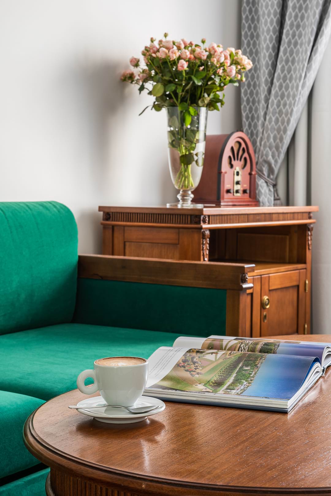 Zielona sofa, drewniany stolik z kawą, radio i wazon kwiatów