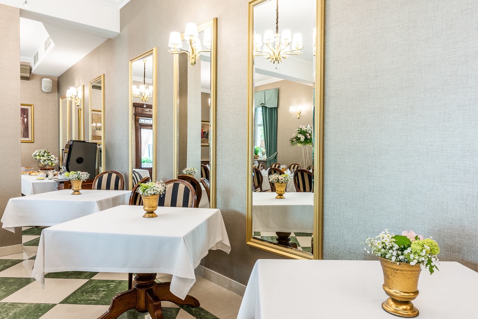 Elegancka sala restauracyjna z lustrami w złotych ramach i kwiatami