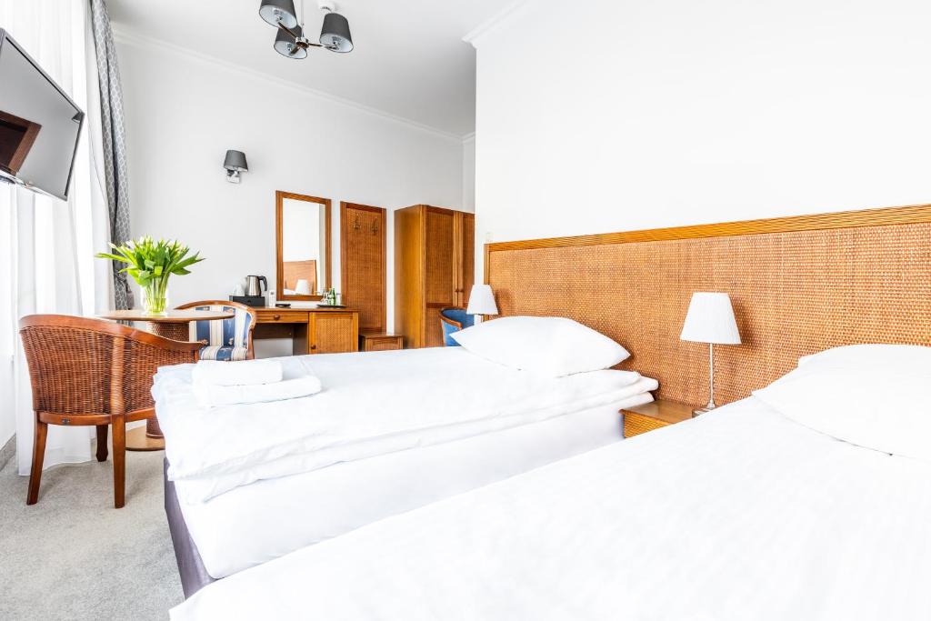 Dwa łóżka z białą pościelą, rattanowy zagłówek i drewniane meble