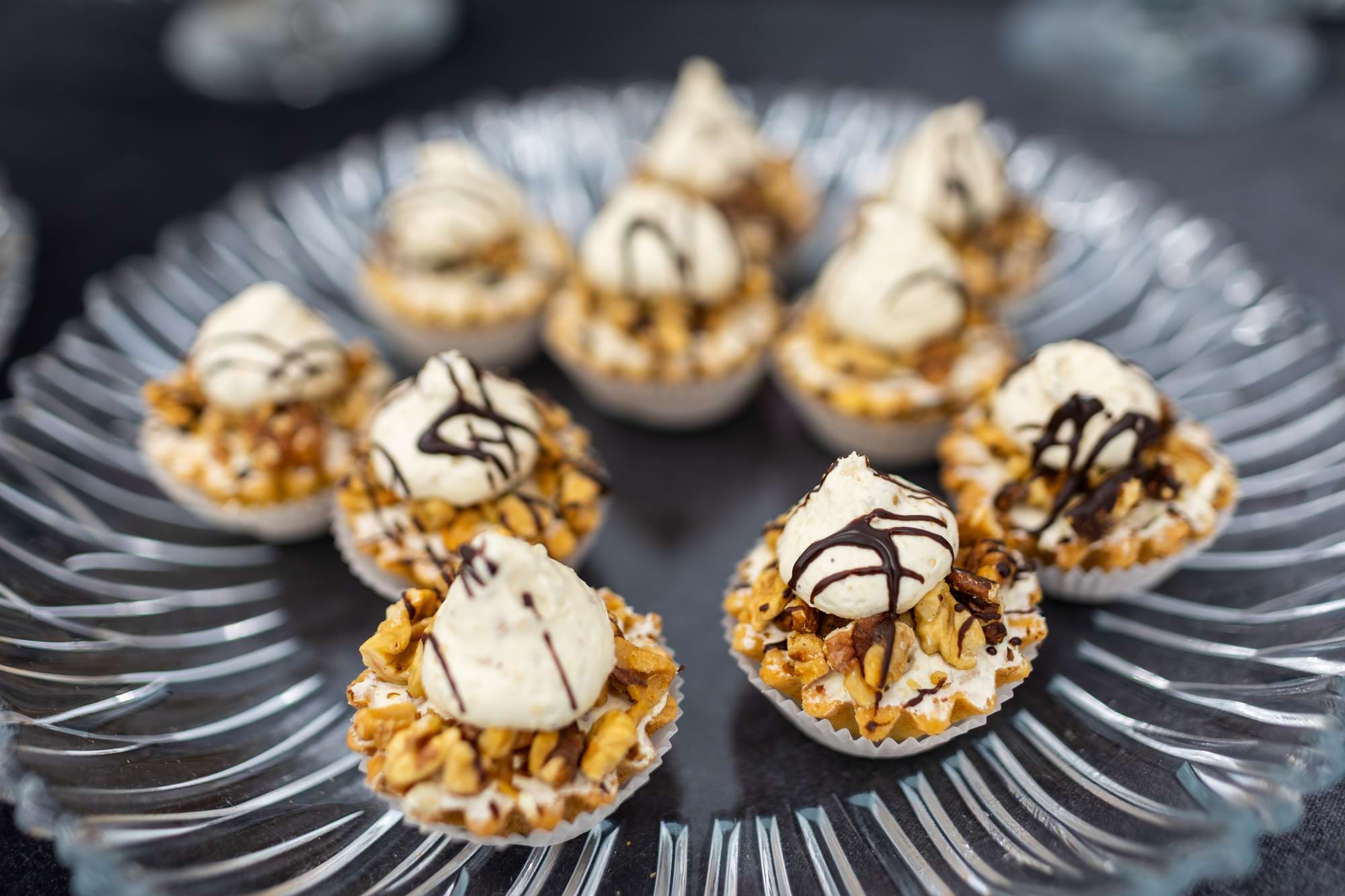 Mini tarty z kremem i polewą czekoladową na szklanej paterze