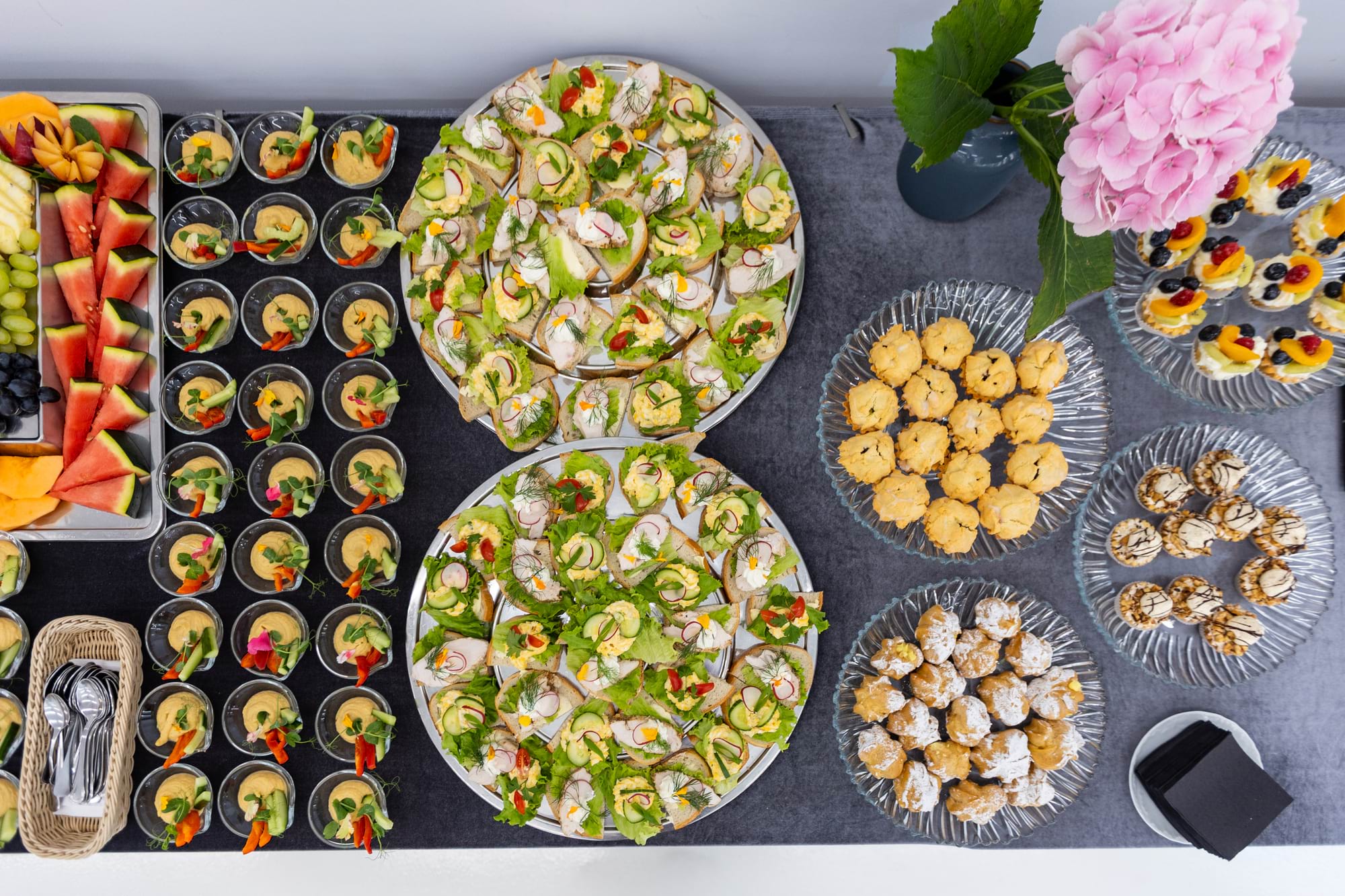 Stół z różnorodnymi przekąskami: kanapki, dipy, owoce i ciasteczka