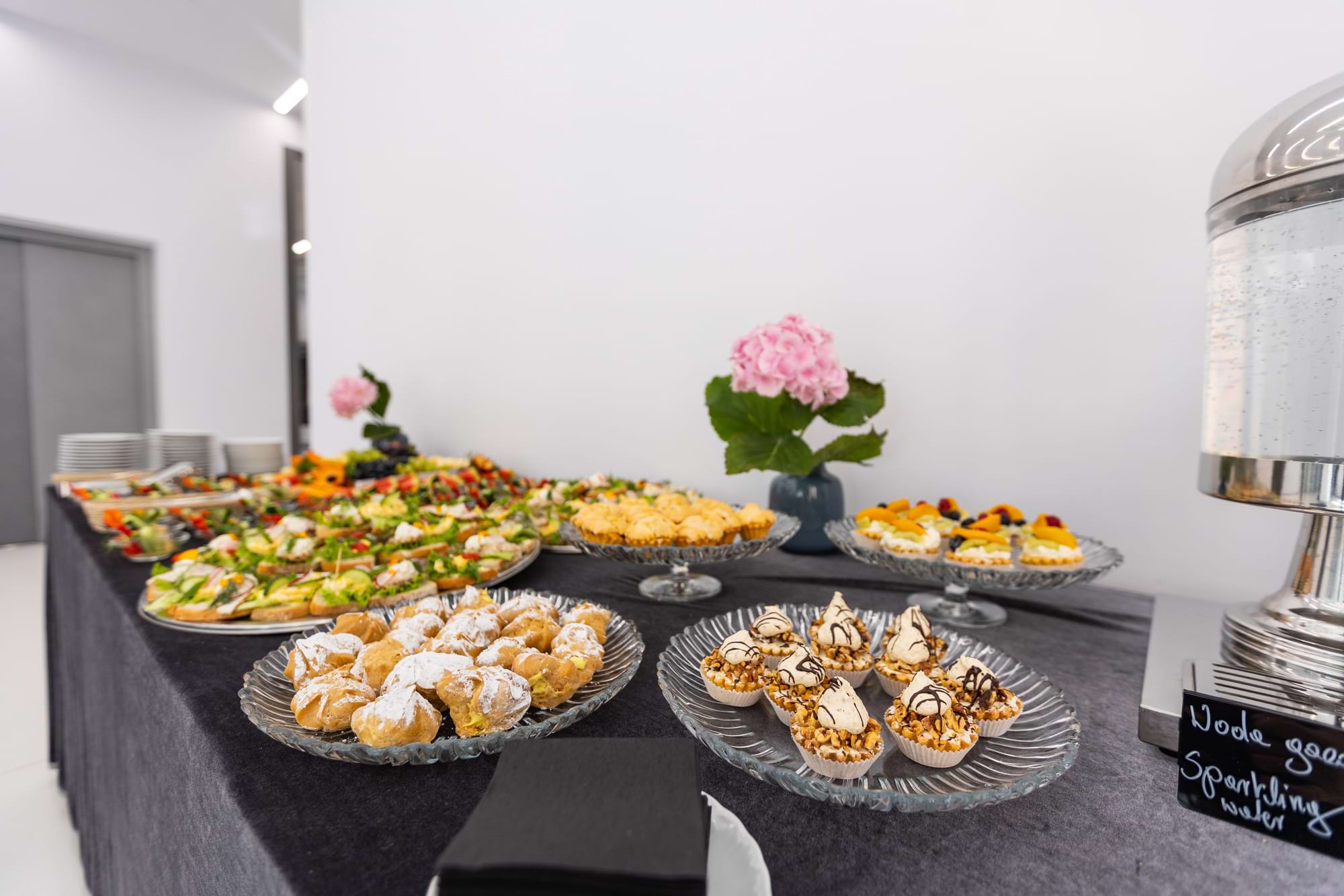Stół z przystawkami i słodkościami, ozdobiony różową hortensją