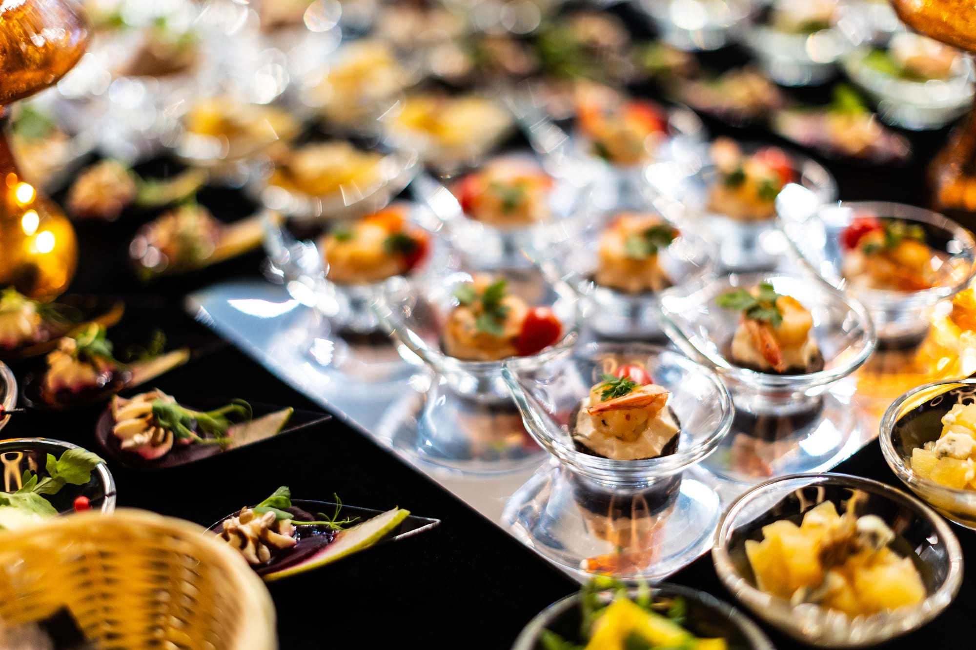 Przystawki w szklanych pucharkach ułożone na błyszczącym stole