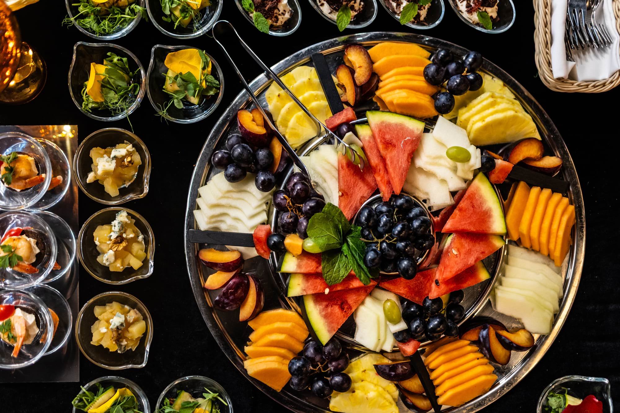 Okrągły talerz pełny kolorowych owoców na czarnym stole