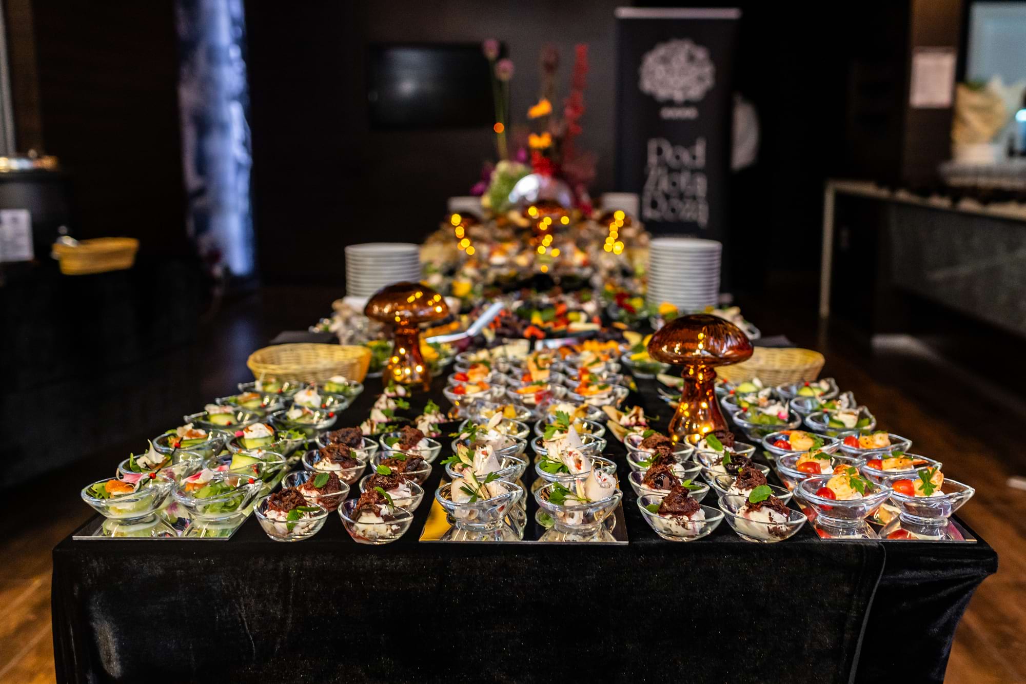 Duży stół z przystawkami w szklanych miseczkach, ozdobne grzybki