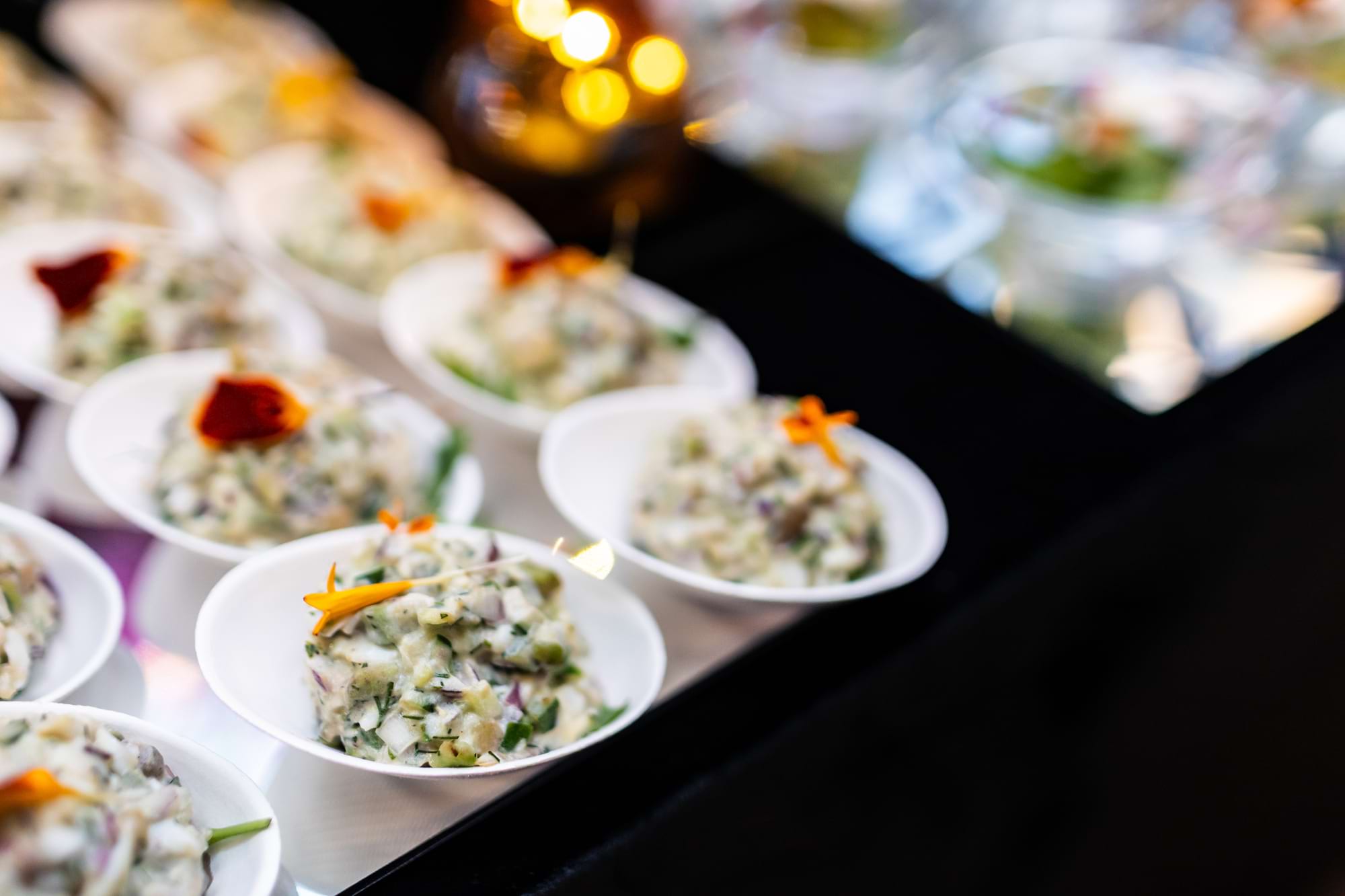 Kremowa sałatka w białych miseczkach z pomarańczowym kwiatem na wierzchu