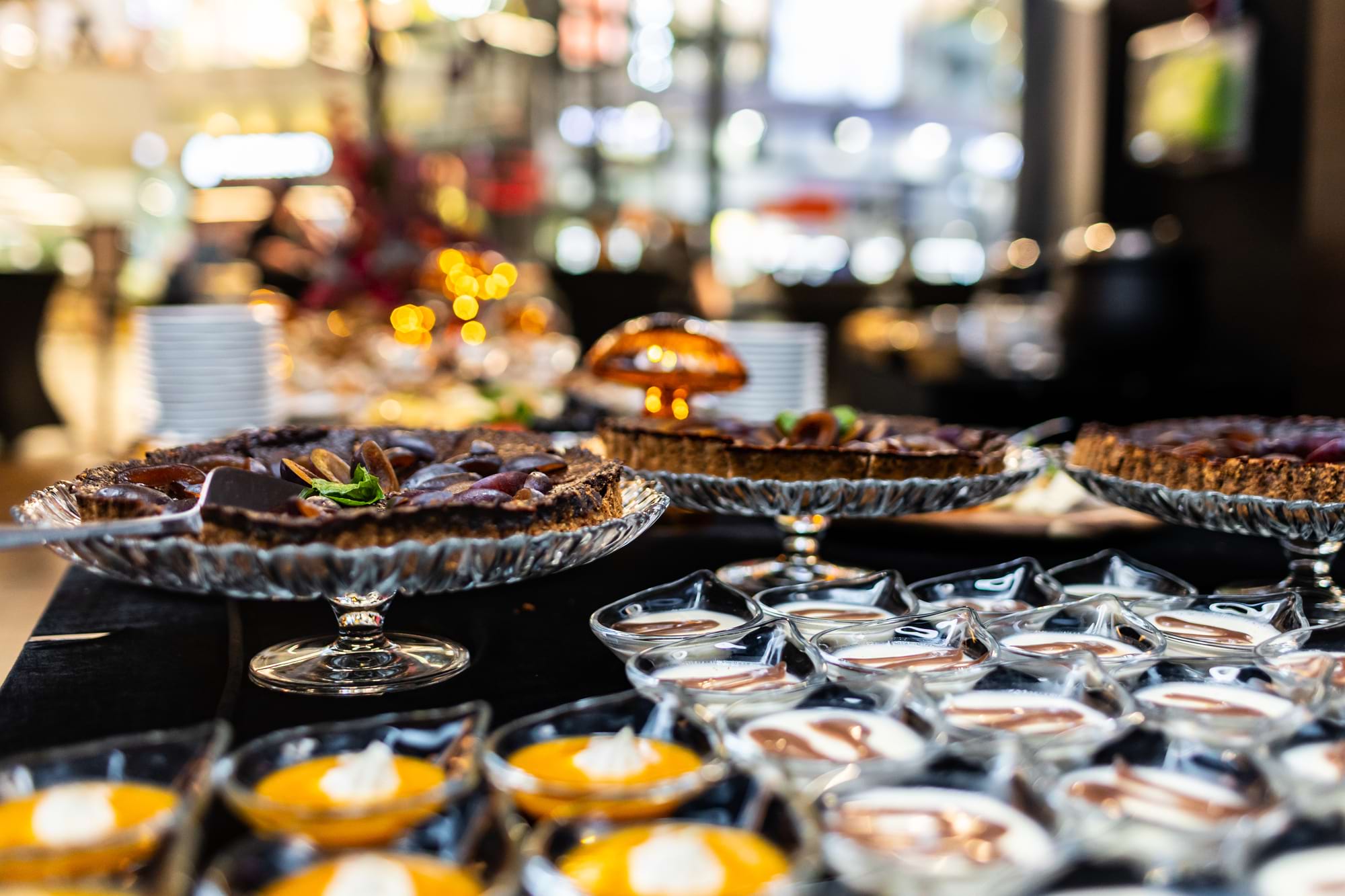 Tarty na szklanych paterach z dodatkami, przed nimi miseczki z sosami