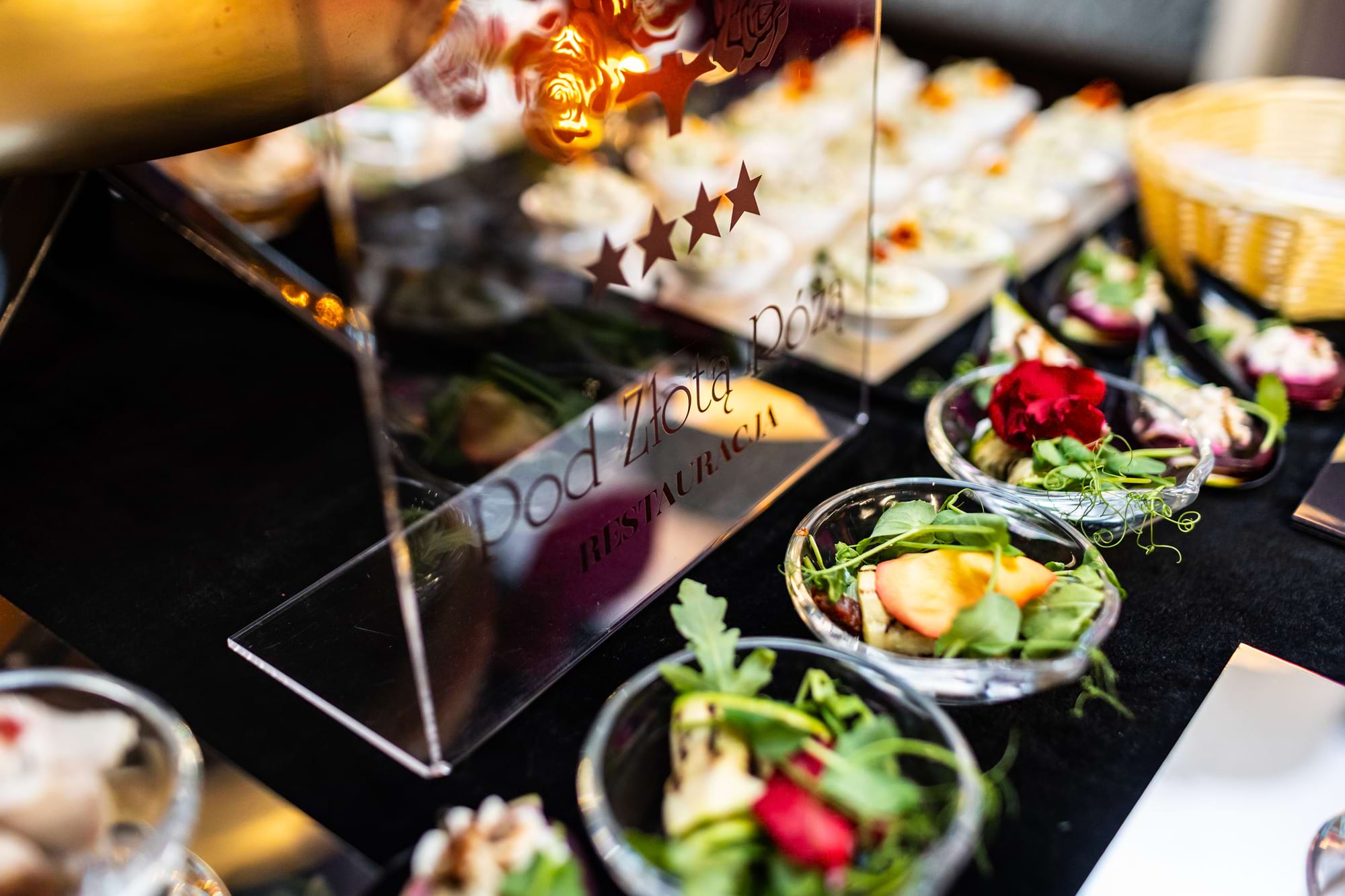 Kolorowe sałatki w miseczkach na czarnym stole, szyld z gwiazdkami