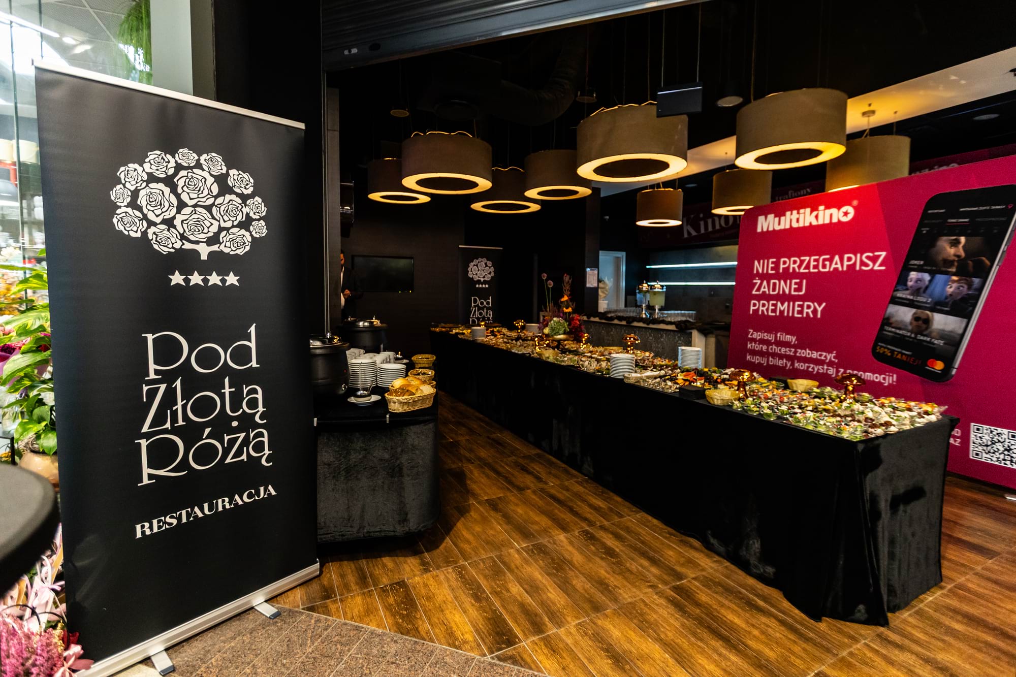 Bufet z potrawami w restauracji Pod Złotą Różą, czarne tło i lampy